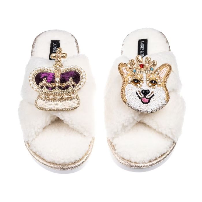 Cream slippers with an embroidered crown and corgi brooch on the top.