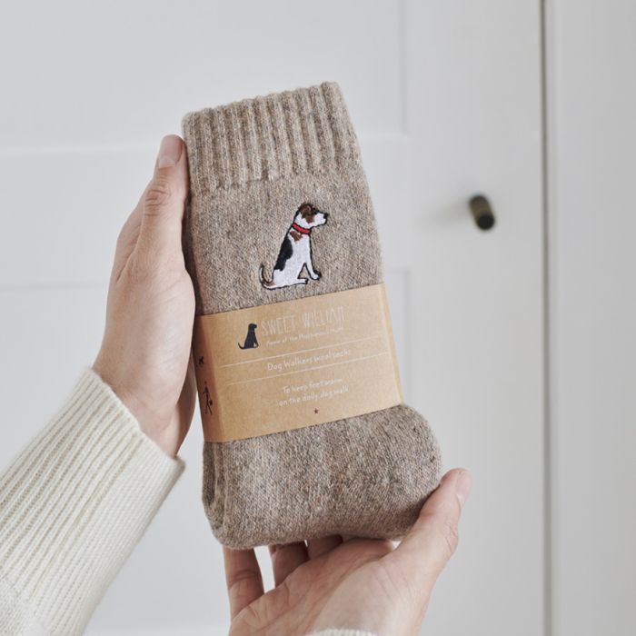 A pair of light-brown socks with an embroidered white, black and brown Jack Russell on the ankle.