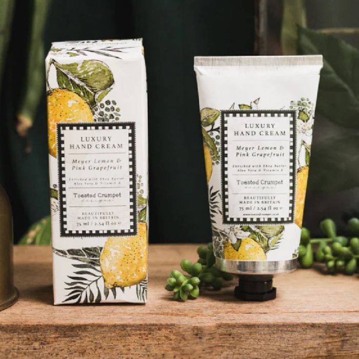 Luxury Meyer lemon and pink grapefruit hand cream with illustrated citrus packaging, displayed on wooden surface with greenery.
