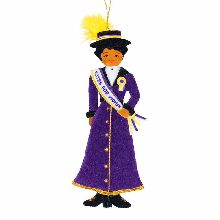 A Suffragette hanging decoration in the shape of a woman wearing a purple dress with a sash that reads votes for women. 