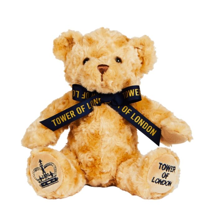 A light-brown bear wearing a navy ribbon with Tower of London written in gold. A navy crown is embroidered on one foot and Tower of London on the other.
