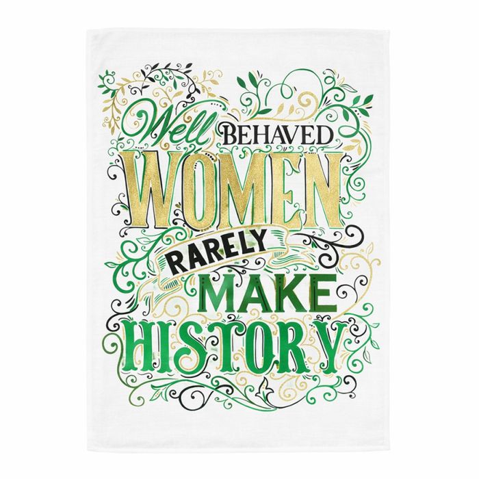 White cotton tea towel with decorative green and gold typography reading “Well behaved women rarely make history”.